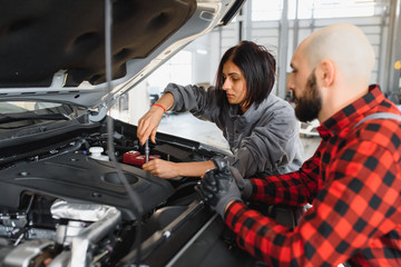 Male and female mechanics working on car