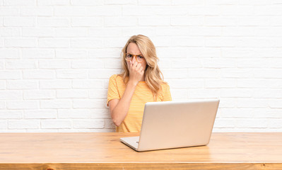 young blonde woman feeling disgusted, holding nose to avoid smelling a foul and unpleasant stench...