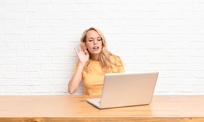 young blonde woman looking serious and curious, listening, trying to hear a secret conversation or...