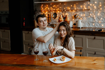 Young couple embrace in kitchen, man and  woman hug.  Lovers drink wine in a modern kitchen interior. 