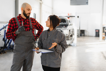 Auto car repair service center. Mechanic examining car engine. Female Mechanic working in her workshop. Auto Service Business Concept. Pro Car female Mechanic Taking Care of Vehicle.