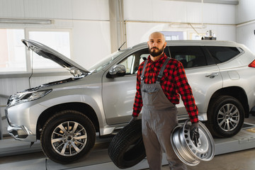 Mechanic holding a tire tire at the repair garage. replacement of winter and summer tires.