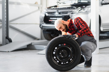 Mechanic holding a tire tire at the repair garage. replacement of winter and summer tires.