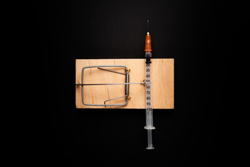 Mousetrap with a bait in the form of a syringe. Stock photo concept of addiction / diabetes.
