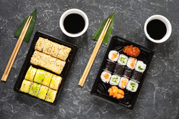 Various kinds of sushi served on black stone background.