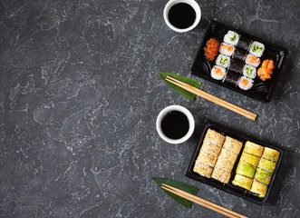 Various kinds of sushi served on black stone background.
