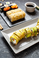 Various kinds of sushi served on black stone background