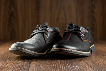 Black shoes one clean second dirty on a wooden background. The concept of shoe shine, clothing care, services.