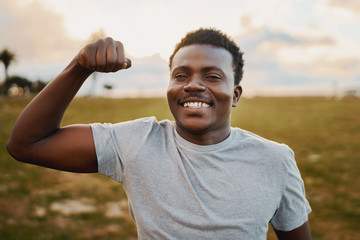 Portrait of a cheerful young athlete smiling and giving punch in front of camera at park