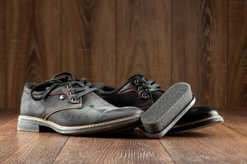 Black shoes one clean second dirty and brush on a wooden background. The concept of shoe shine, clothing care, services.