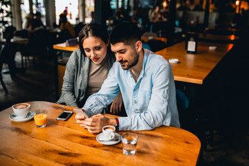friends in cafeteria using mobile phone