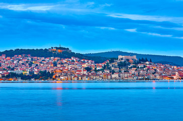 Fototapeta na wymiar Large panorama of Unesco heritage historic town of Sibenik on Adriatic sea, Dalmatia, Croatia. Shot from the sea, harbor, waterfront and cathedral in front. Dramatic red sky at night. Evening city..