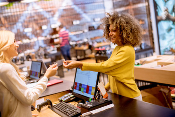 Happy woman customer paying with credit card in fashion showroom