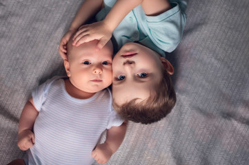 Brother hugs his newborn brother. The kid meets a new brother. . Family with children at home. Love, trust and tenderness