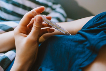 Female holds a thermometer in her hands to measure temperature. coronavirus disease concept, symptoms