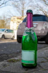 Auf dem Bordstein stehende leere Sektflasche
