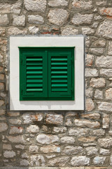 Stone house with window with shutters. A bunch of wooden window shutters pattern on white stone wall. Naked worn wooden and plain painted shutters. Hipster loft wallpaper.