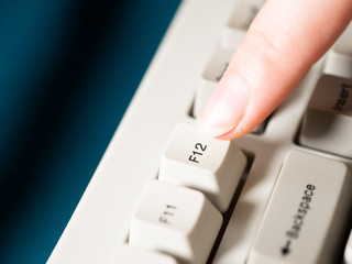 Female forefinger pushes F12 button. Close-up