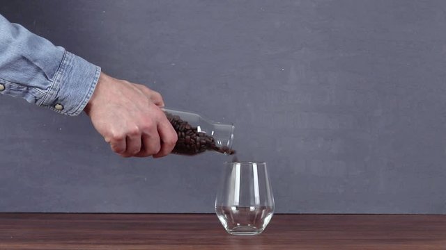 A man filling a coffee bean from a bottle full of coffee beans into an empty glass. isolated background