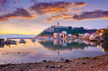 Naklejka premium Town of Vrbnik (Verbnik) harbor view morning glow, Island of Krk, Kvarner bay archipelago, Croatia, Europe. Dramatic summer seascape of Adriatic sea. Stone beach. Incredible morning cityscape.