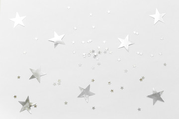 Silver confetti and stars and sparkles on a light background. Top view, flat lay. Copy text....