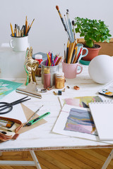 Artist studio with paper and utensils. Workspace of designer illustrator with lots of materilals and equipement.