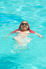 Fototapeta na wymiar Young cheerful woman with african pigtails swims in the pool.