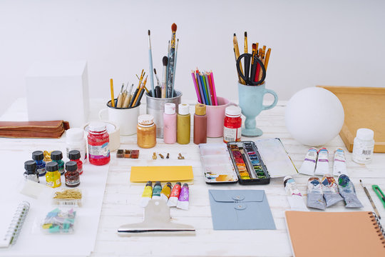 Artist studio with paper and utensils. Workspace of designer illustrator with gypsum shapes, pencils, brushes and paint bottles. Freelance creative concept