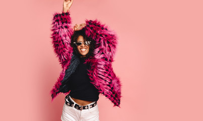 Black woman in a black faux fur jacket, Close up fashion portrait of crazy hipster African girl with funny curly hairstyle and vivid faux fur coat, urban trendy style. Horizontal.copy space - obrazy, fototapety, plakaty