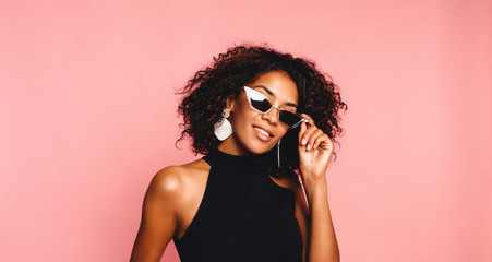 Beautiful african american girl with an afro hairstyle smiling. Portrait of happy young black woman laughing against pink wall.Blissful lovable woman with african hairstyle laughing indoor - Powered by Adobe