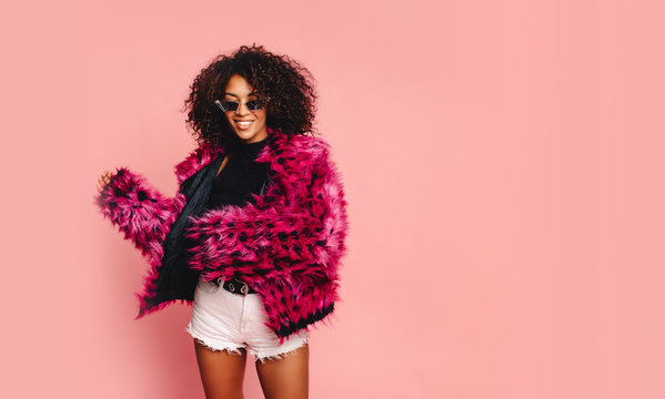 Black woman in a black faux fur jacket, Close up fashion portrait of crazy hipster African girl with funny curly hairstyle and vivid faux fur coat, urban trendy style. Horizontal.copy space
