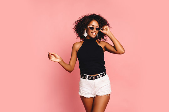 Portrait of smiling young black woman with copy space Fashion pretty young smiling african woman wearing stylish swag outfit at pink background. Horizontal. copy space, shopping.