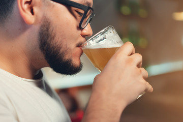 Bearded drink glass of beer. Beer pub. Guy at cafe pub. Beer time. Cheerful young man drinks beer at the bar . People, lifestyle, recreation, pause, break concept