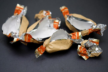 Empty candy wrappers close-up. Packages of chocolates on a black background. Weight gain concept, living hard without sweets.