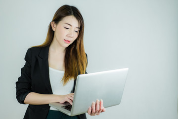 Portrait of beautiful asian business woman holding and typing a laptop. Caucasian female model isolated on white background.