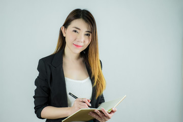 Portrait of beautiful asian business woman holding a notebook and writing. Caucasian female model isolated on white background.