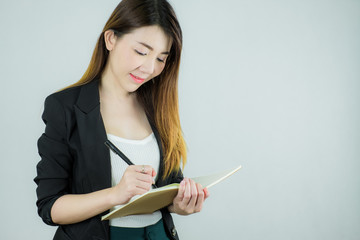 Portrait of beautiful asian business woman holding a notebook and writing. Caucasian female model isolated on white background.