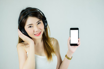 Portrait of beautiful asian woman with headphones and mobile device. Showing empty white screen. Caucasian female model isolated on white background.