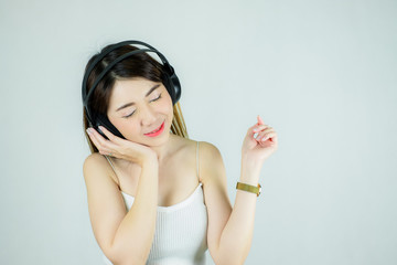 Portrait of beautiful asian woman with headphones listening to music.  happy, smiling / Caucasian female model isolated on white background.