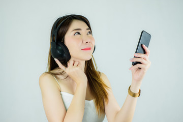 Portrait of beautiful asian woman with headphones and mobile device listening to music.  happy, smiling / Caucasian female model isolated on white background.