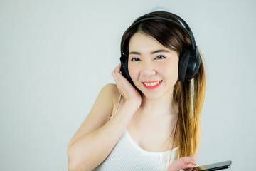 Portrait of beautiful asian woman with headphones and mobile device listening to music.  happy, smiling / Caucasian female model isolated on white background.