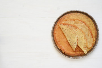 Thin crepes on a white wooden background.