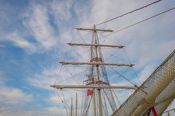 Rigging of a tall ship below a blue cloudy sky in sunlight in winter