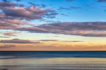 Beautiful colorful clouds over the sea. Stunning sky after sunset.