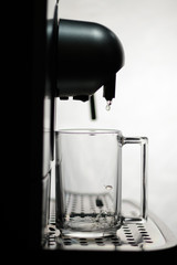 Coffee machine is preparing to brew coffee in a glass cup on a white background. Cappuccino,...