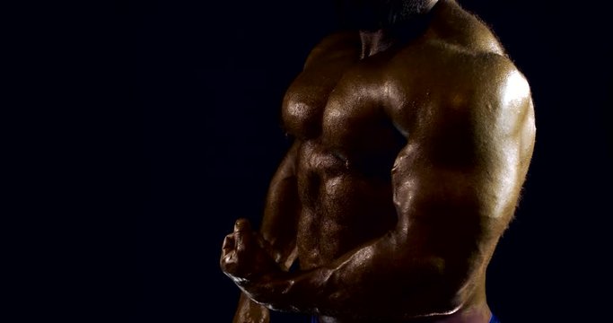 Close-up portrait of a male naked body of a bodybuilder, he is in the Studio on a black background, Posing, showing all the muscles and muscles.