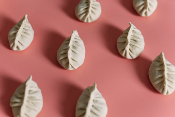 Semi-finished products on a pink background. Top view of manti or dumplings. Pattern