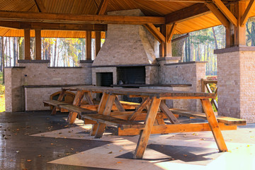 A large professional industrial  stone oven grill for cooking frying food from a stone tiled on a stone wall in the open air street. Big wooden table in the foreground