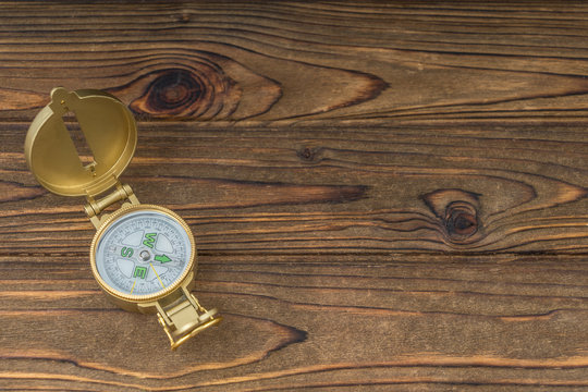 Golden old compass on a wooden table background. The concept of tourism, orientation, navigation. Copy space