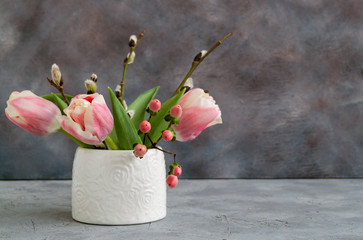 spring flowers in a white vase on a gray background.